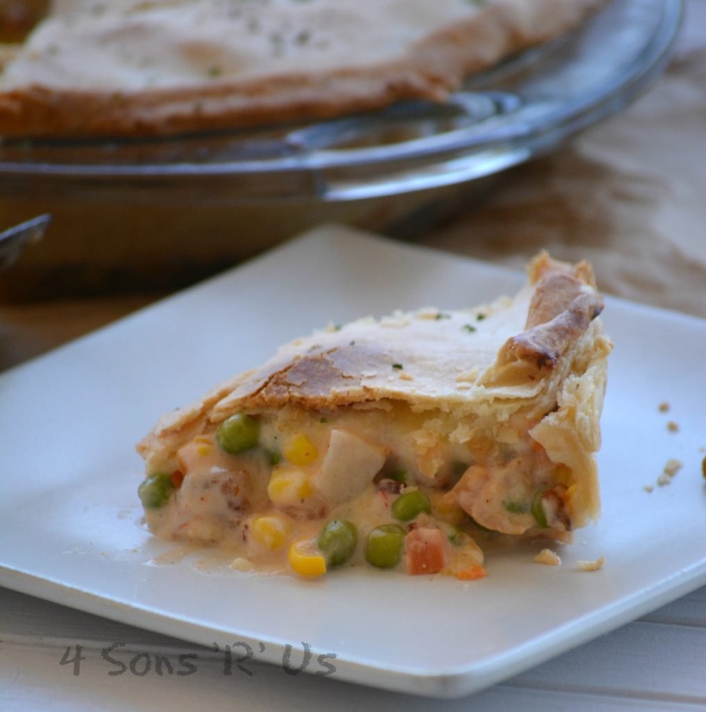 a slice of Seafood Pot Pie on a white plate showing the creamy filling with veggies and chunks of seafood under a crisp crust