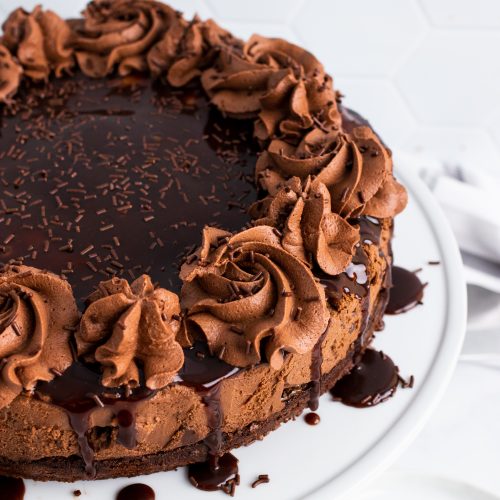 hot fudge brownie cheesecake on a white cake pedestal