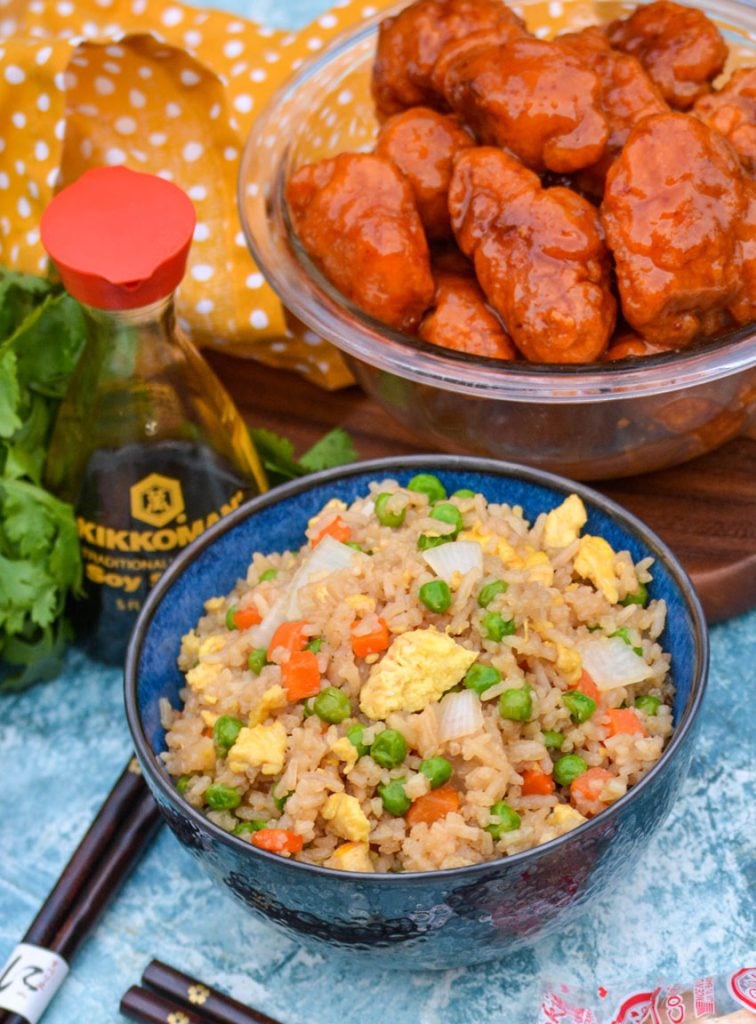 a bowl shown full of this copy cat fried rice with a bottle of soy sauce and a bowl of orange chicken in the background