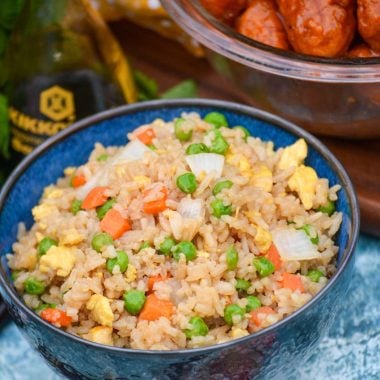 a bowl shown full of this copy cat fried rice with a bottle of soy sauce and a bowl of orange chicken in the background