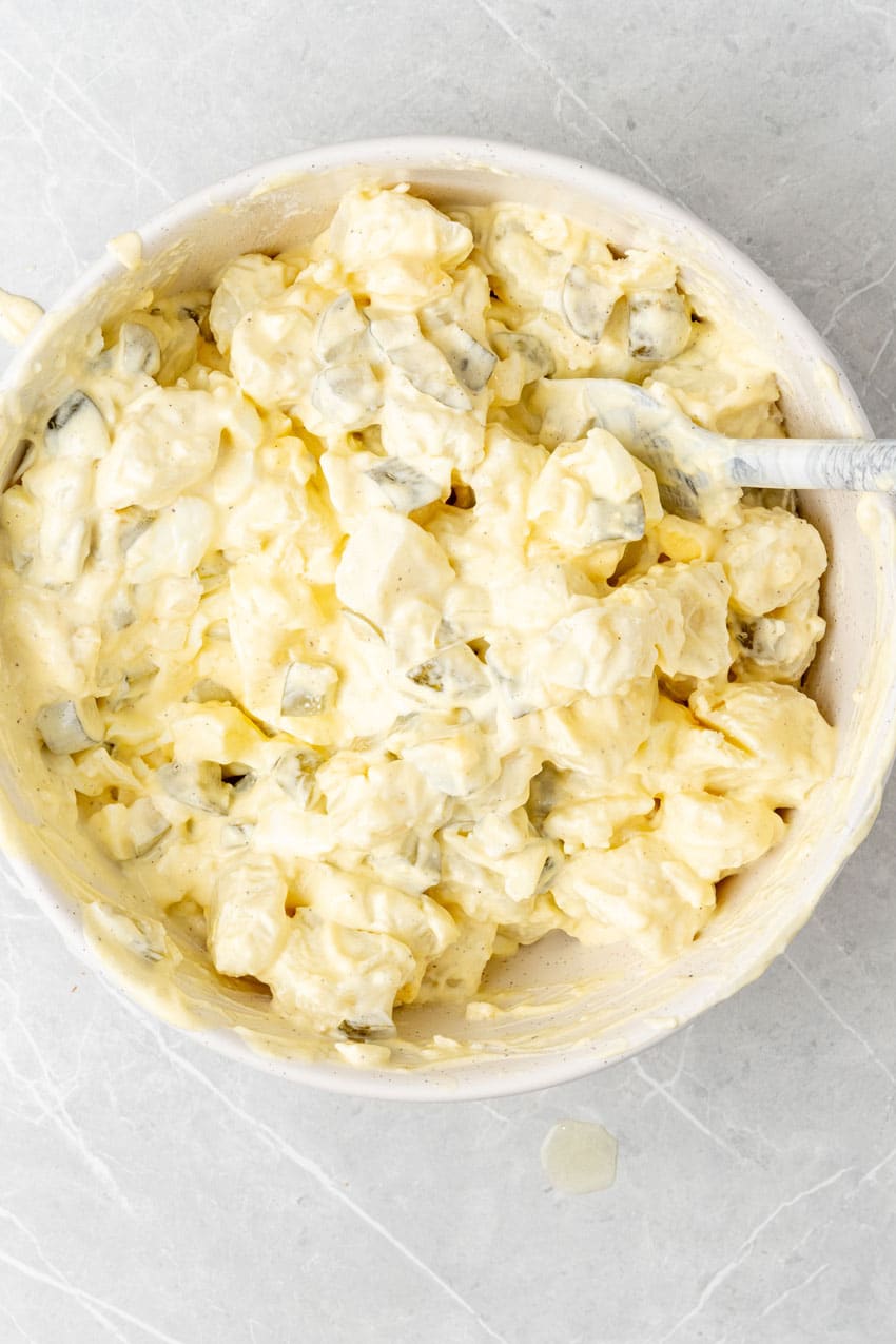 creamy dill pickle potato salad in a large white mixing bowl