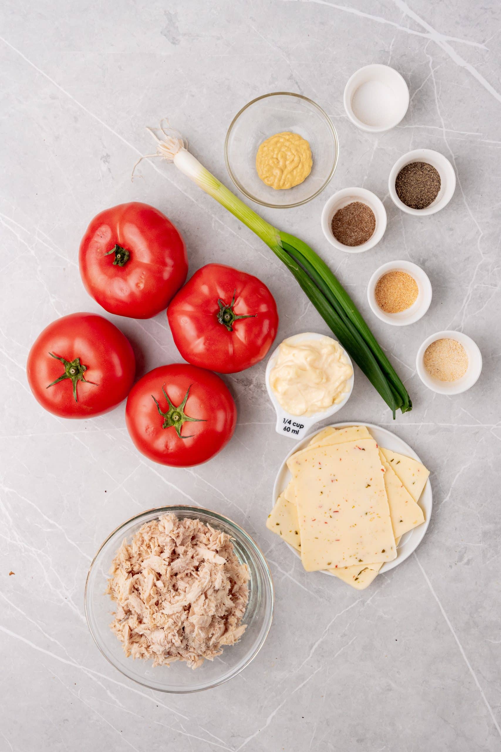 an overhead image showing the measured ingredients needed to make a batch of tuna melt stuffed tomatoes