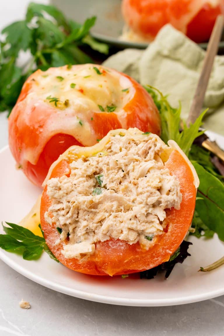 tuna melt tomatoes served on a white plate with salad greens on the side