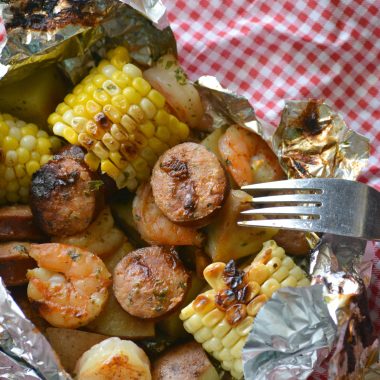 low country boil in an opened aluminum foil packet with a silver fork resting on the side