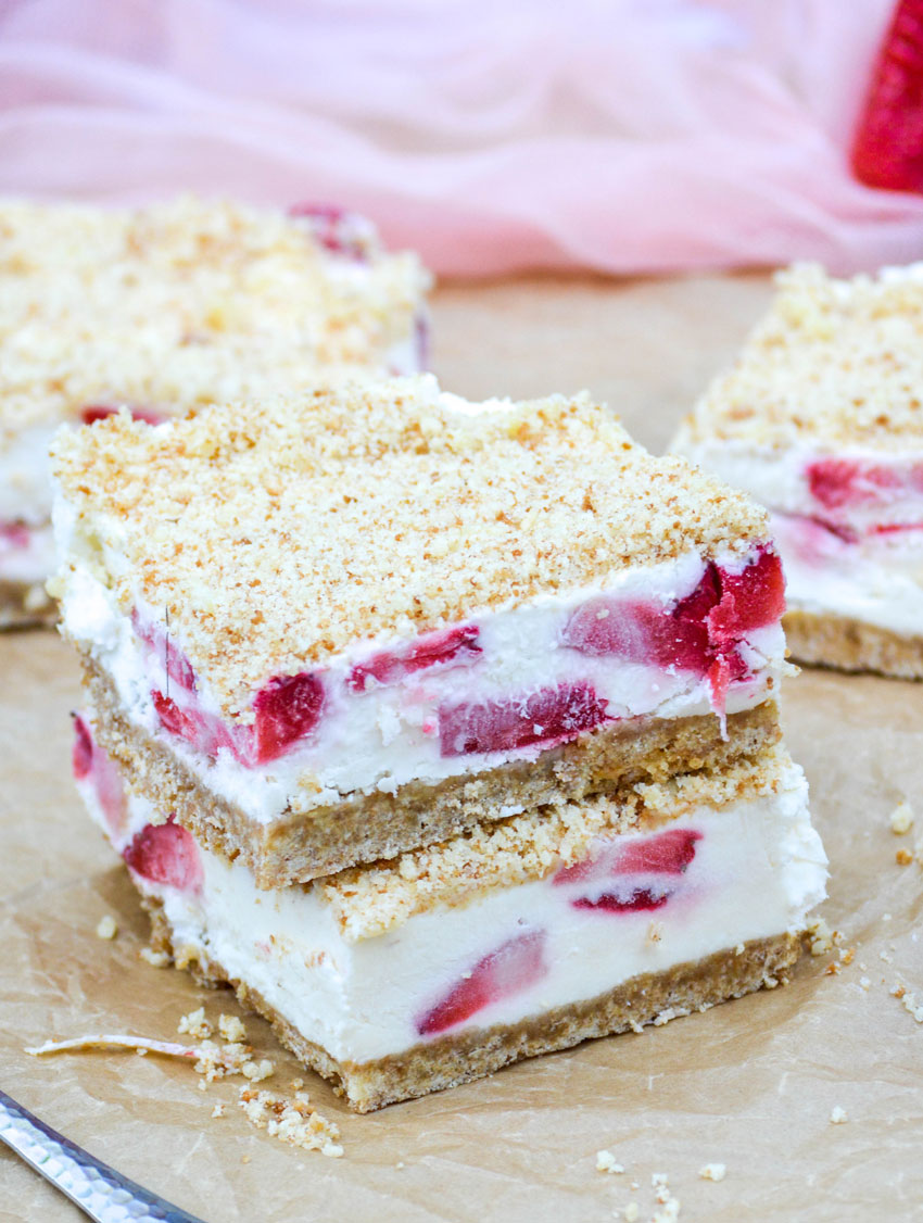 two strawberry crunch bar squares stacked together on a crinkled sheet of brown parchment paper