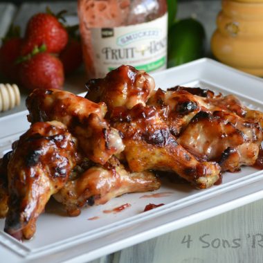 STRAWBERRY JALAPENO CHICKEN WINGS ON A LARGE WHITE SERVING PLATTER WITH FRESH STRAWBERRIES ON THE SIDE