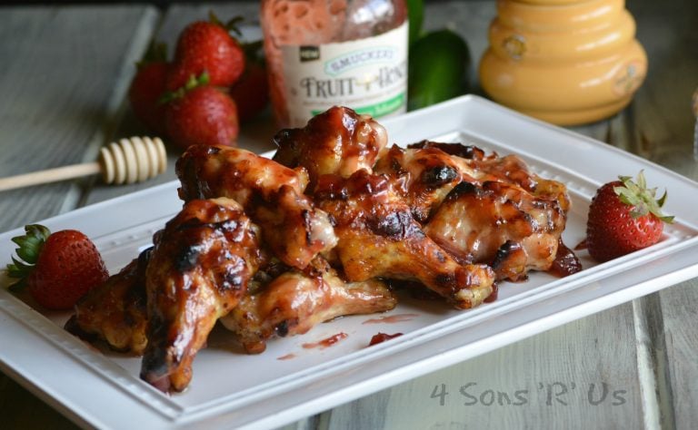 STRAWBERRY JALAPENO CHICKEN WINGS ON A LARGE WHITE SERVING PLATTER WITH FRESH STRAWBERRIES ON THE SIDE