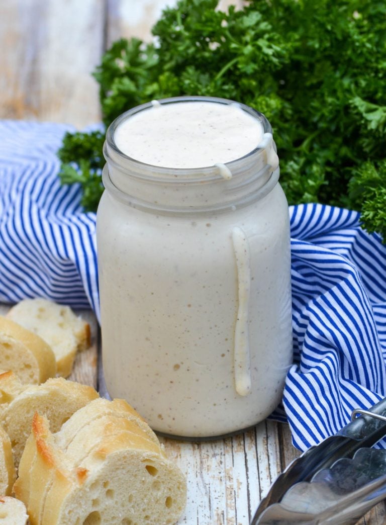 alabama white barbecue sauce in a glass mason jar with some dripping down the side