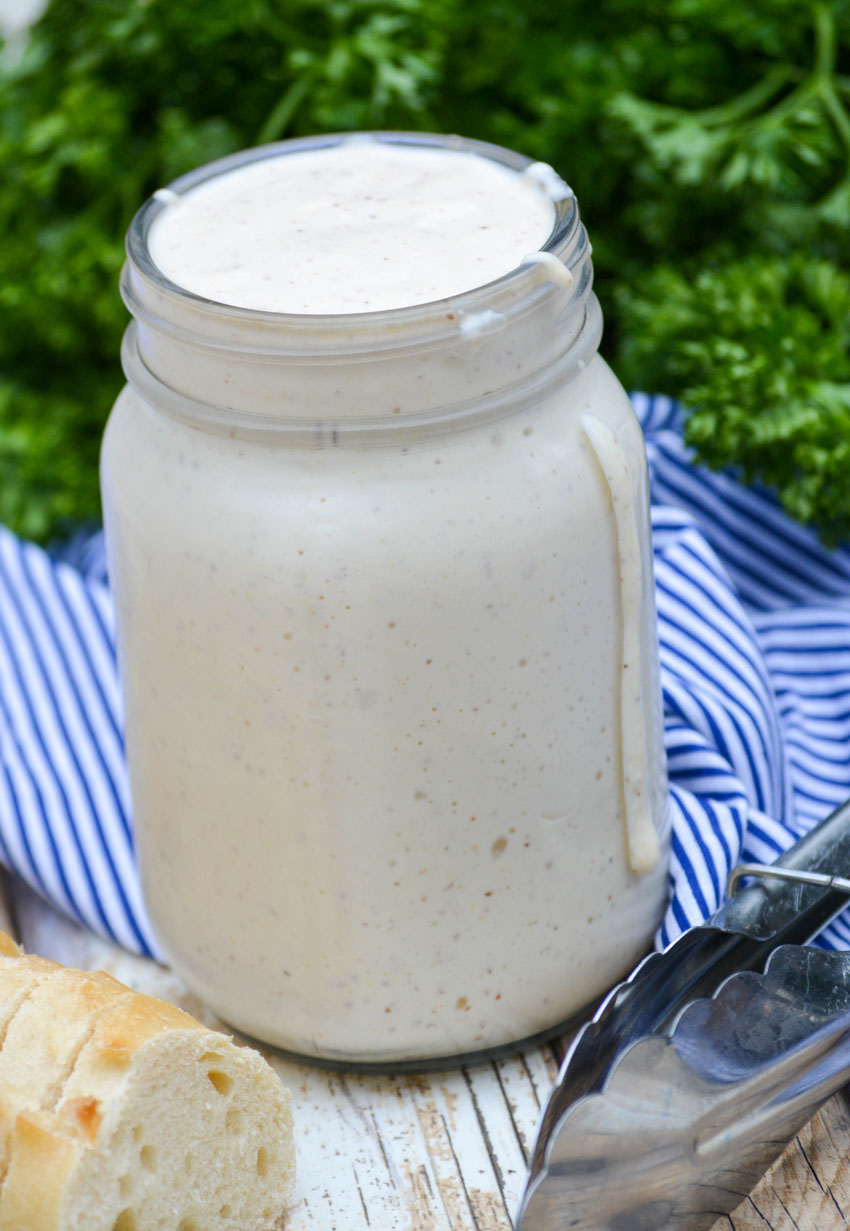 alabama white barbecue sauce in a glass mason jar with some dripping down the side