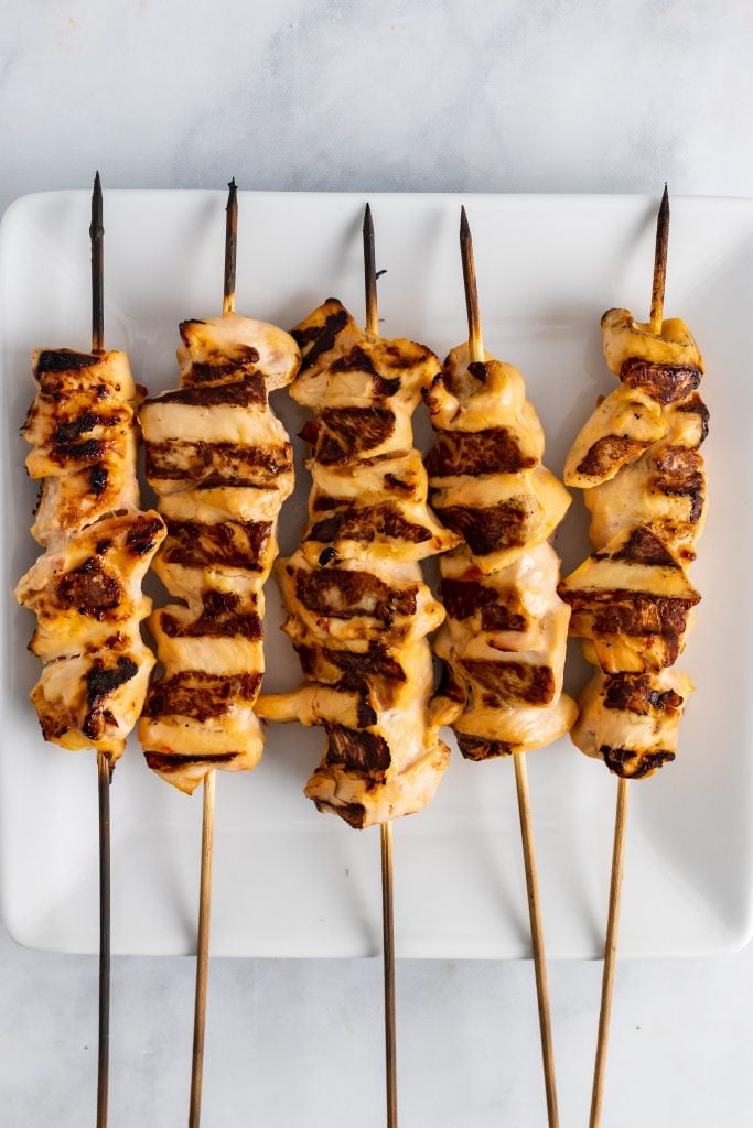 charred chicken kabobs on a white plate