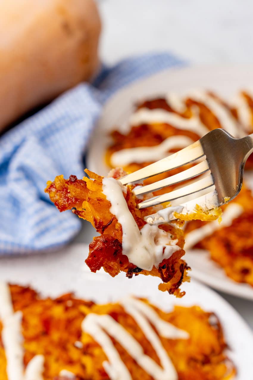 a silver fork holding up a ranch covered piece of a butternut squash fritter