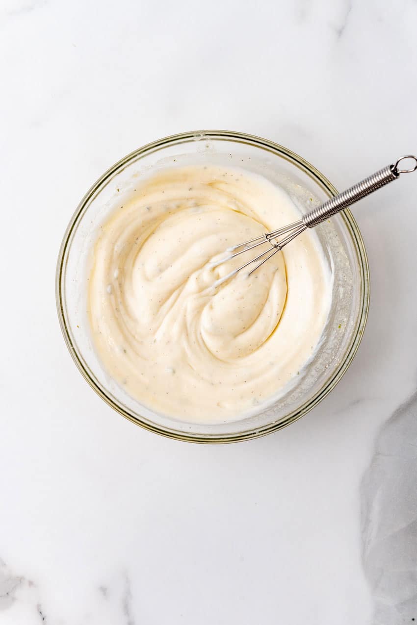 ranch crema in a glass mixing bowl with a wire whisk resting on the side