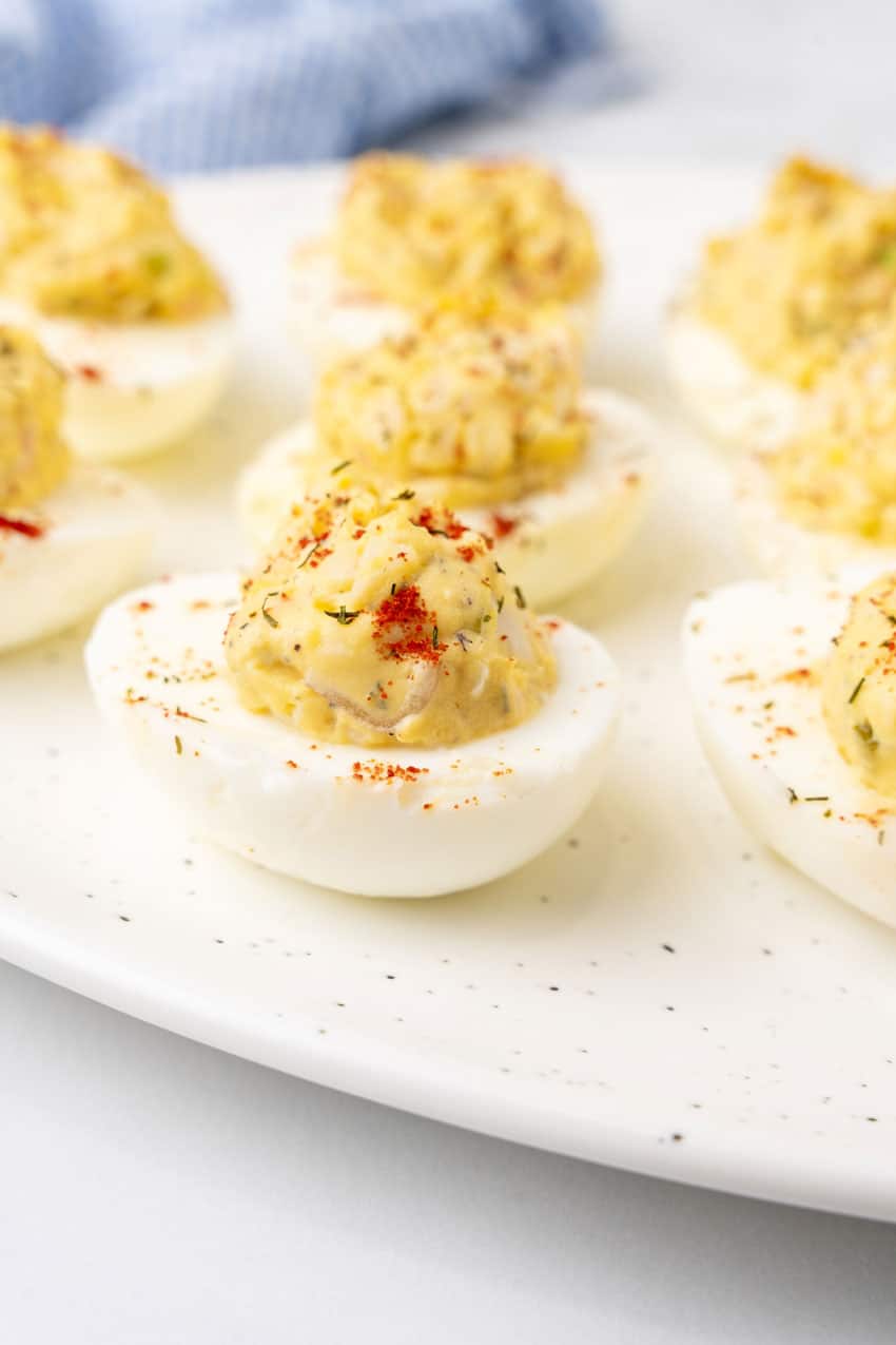 crab stuffed deviled eggs arranged in three rows on a white serving platter