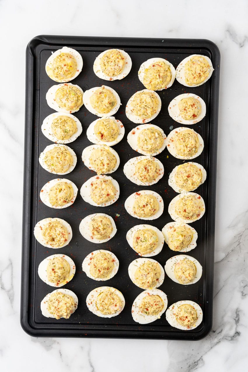 creamy crab stuffed deviled eggs arranged in rows on a metal baking pan