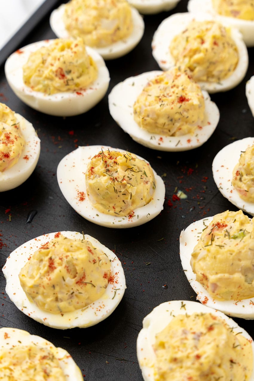 a close up of creamy crab stuffed deviled eggs arranged in rows on a metal baking pan