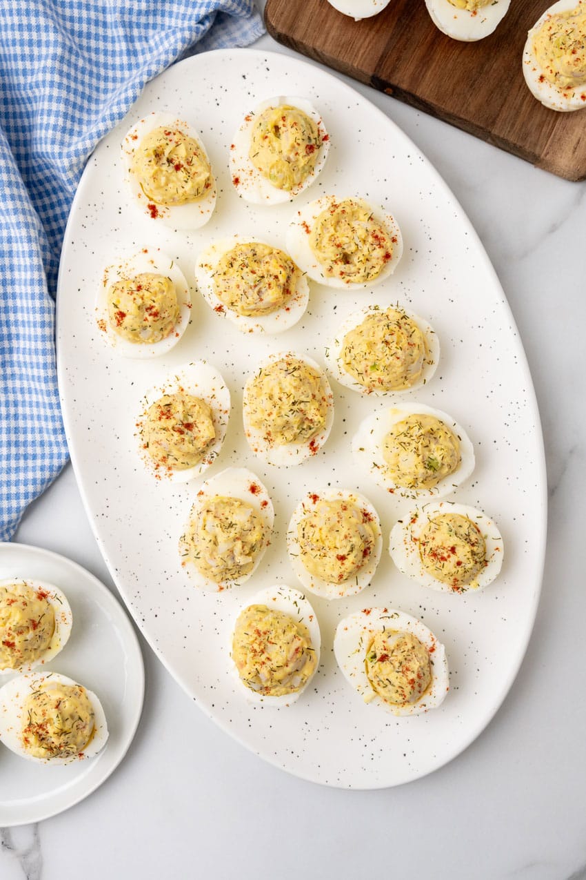 crab stuffed deviled eggs arranged in three rows on a white serving platter