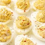 crab stuffed deviled eggs arranged in three rows on a white serving platter