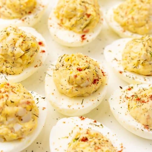 crab stuffed deviled eggs arranged in three rows on a white serving platter