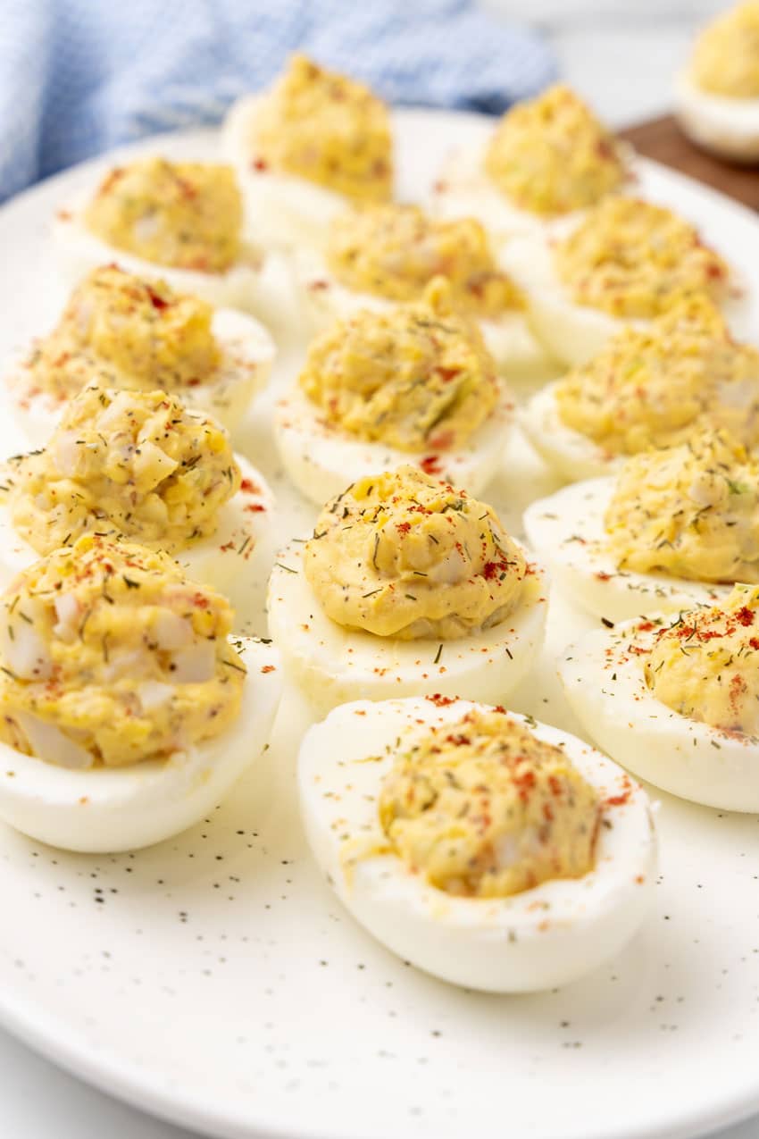 creamy crab deviled eggs arranged in a row on a white serving platter