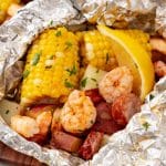 low country boil foil packets on a wooden cutting board