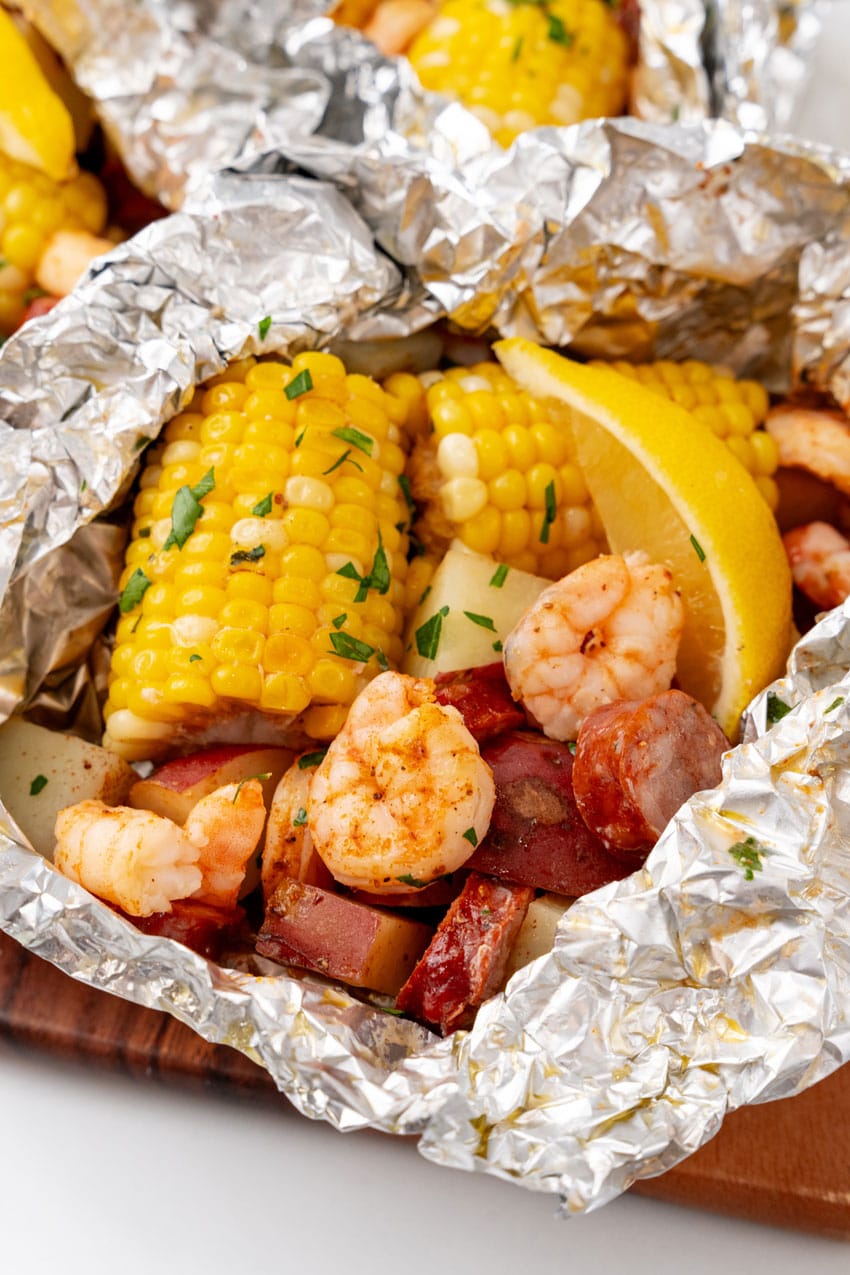 low country boil foil packets on a wooden cutting board