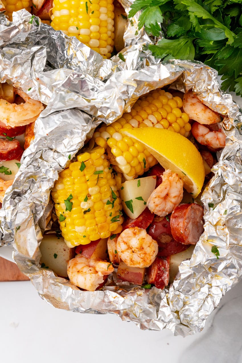 low country boil foil packets on a wooden cutting board