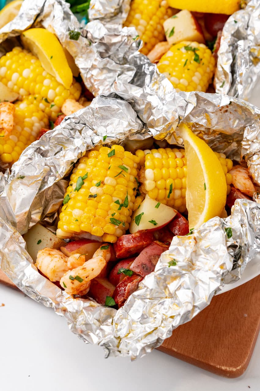 low country boil foil packets on a wooden cutting board