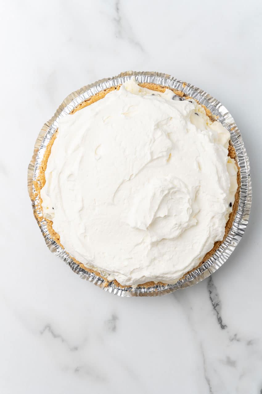 whipped cream topped frozen ice cream pie in a graham cracker crust