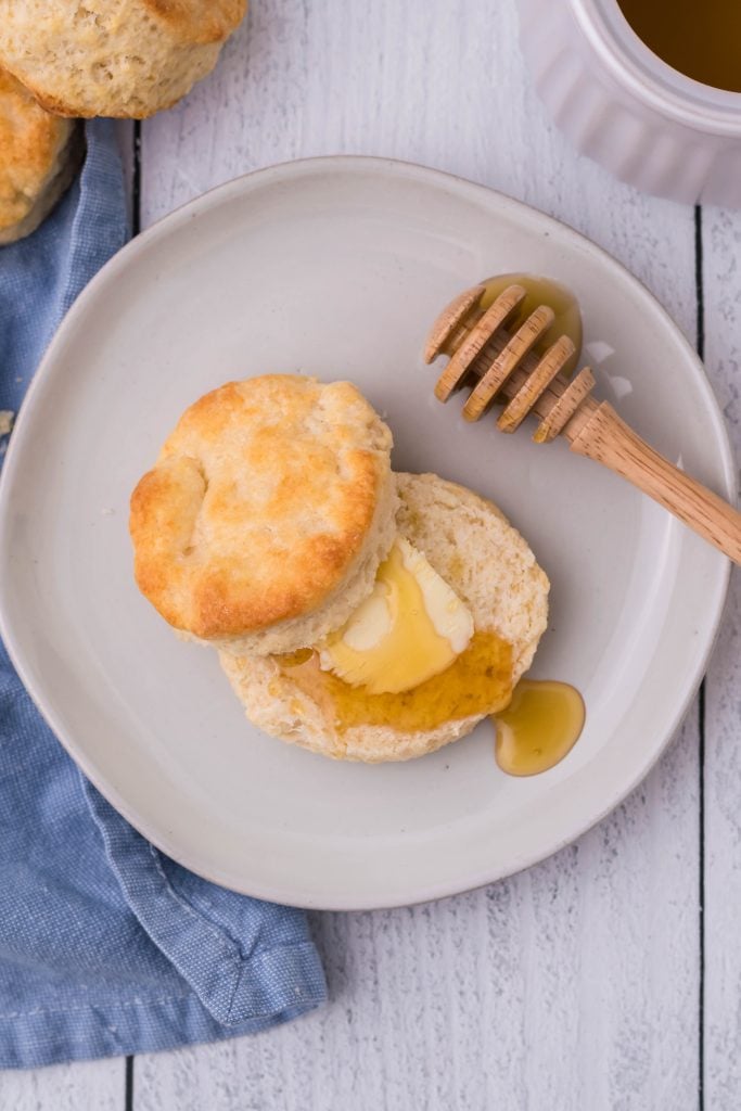 a copycat kfc biscuit topped with a pat of butter and a drizzle of honey