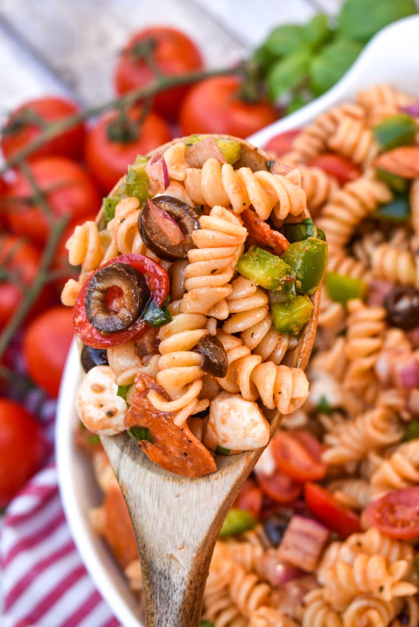 a wooden spoon holding up a scoop of pizza pasta salad