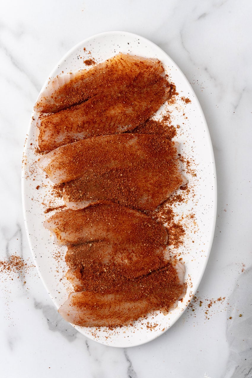 spice rubbed tilapia filets on a white serving platter