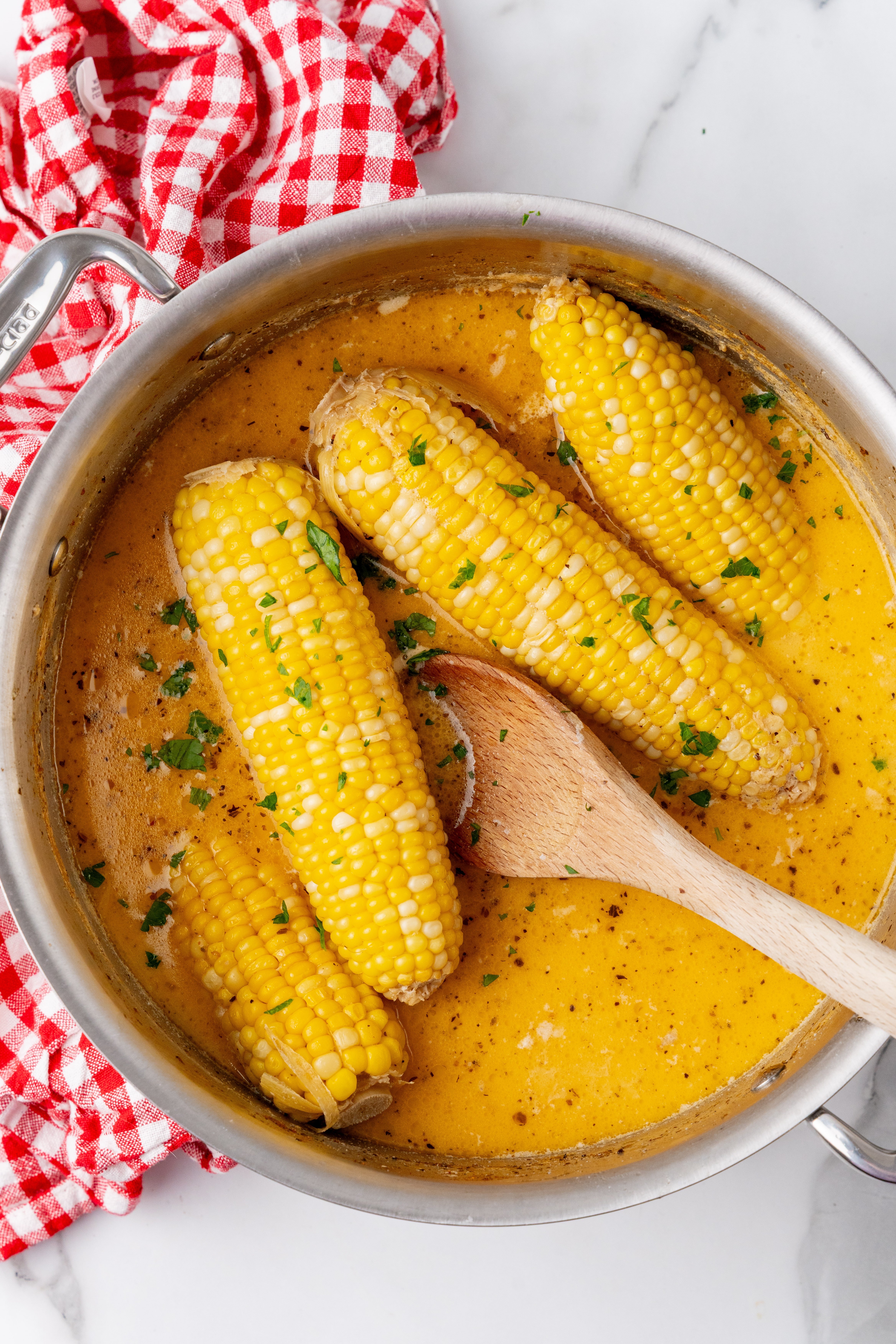 milk and honey corn on the cob in seasoned milk in a silver pan
