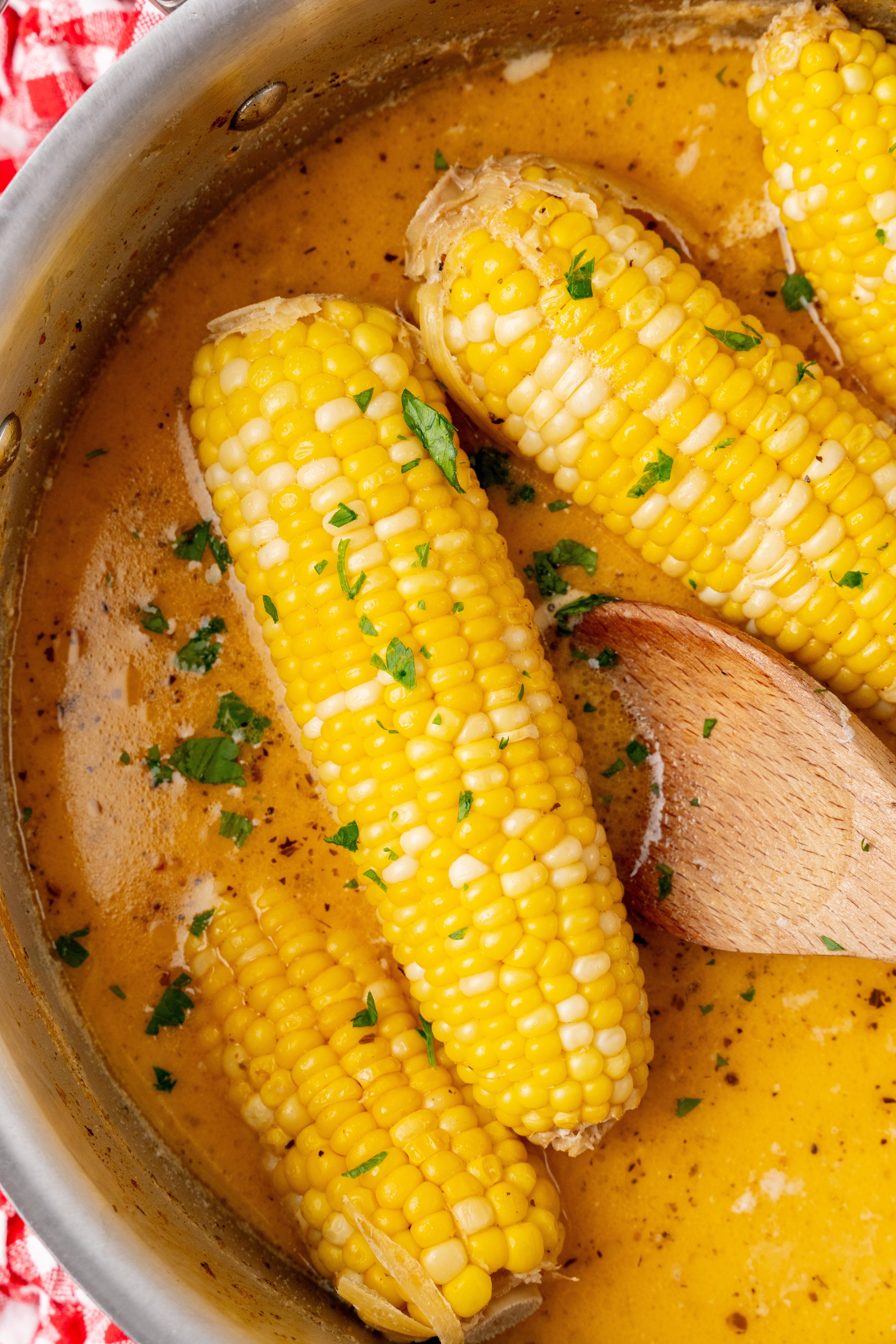 milk and honey corn on the cob in seasoned milk in a silver pan