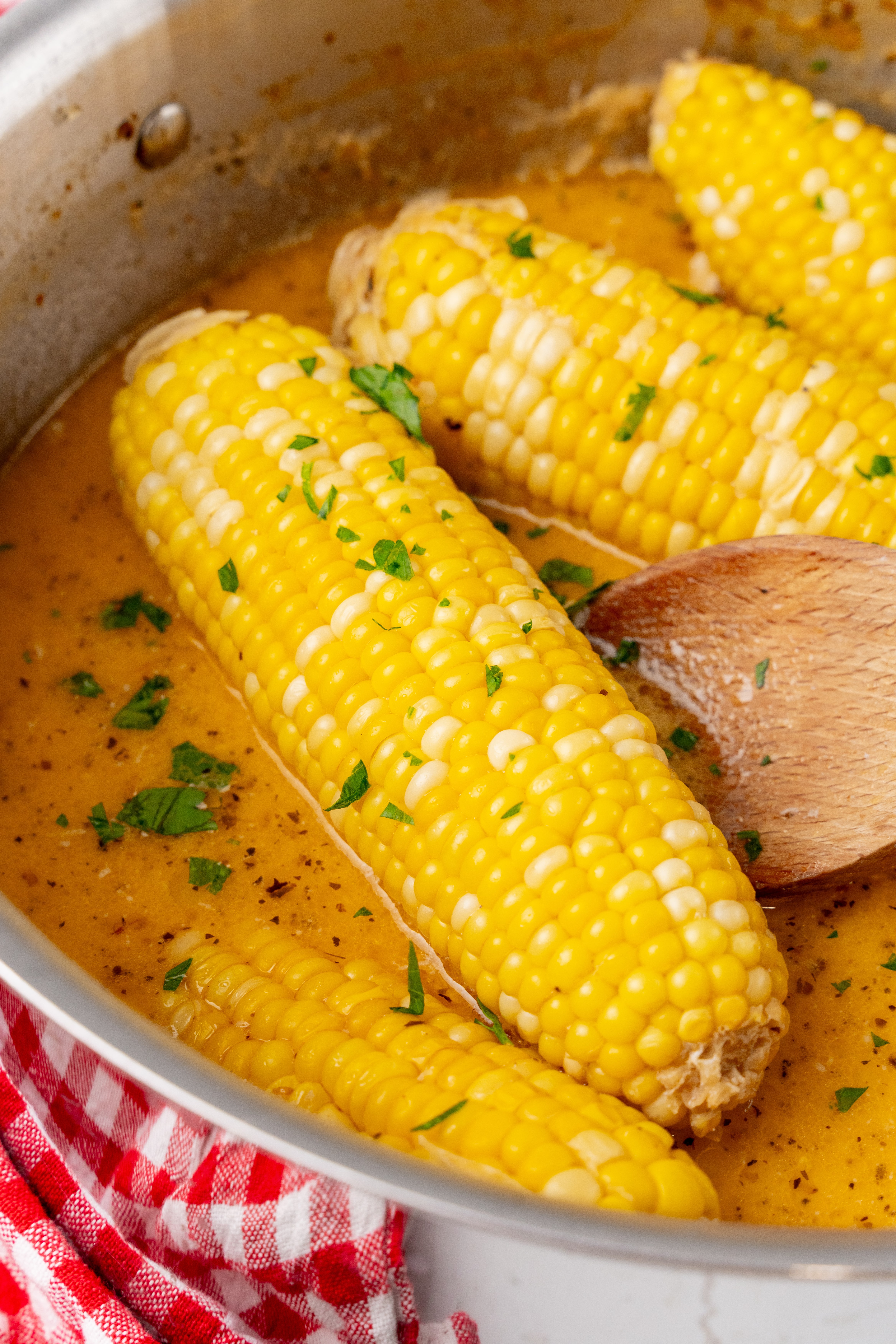 milk and honey corn on the cob in seasoned milk in a silver pan