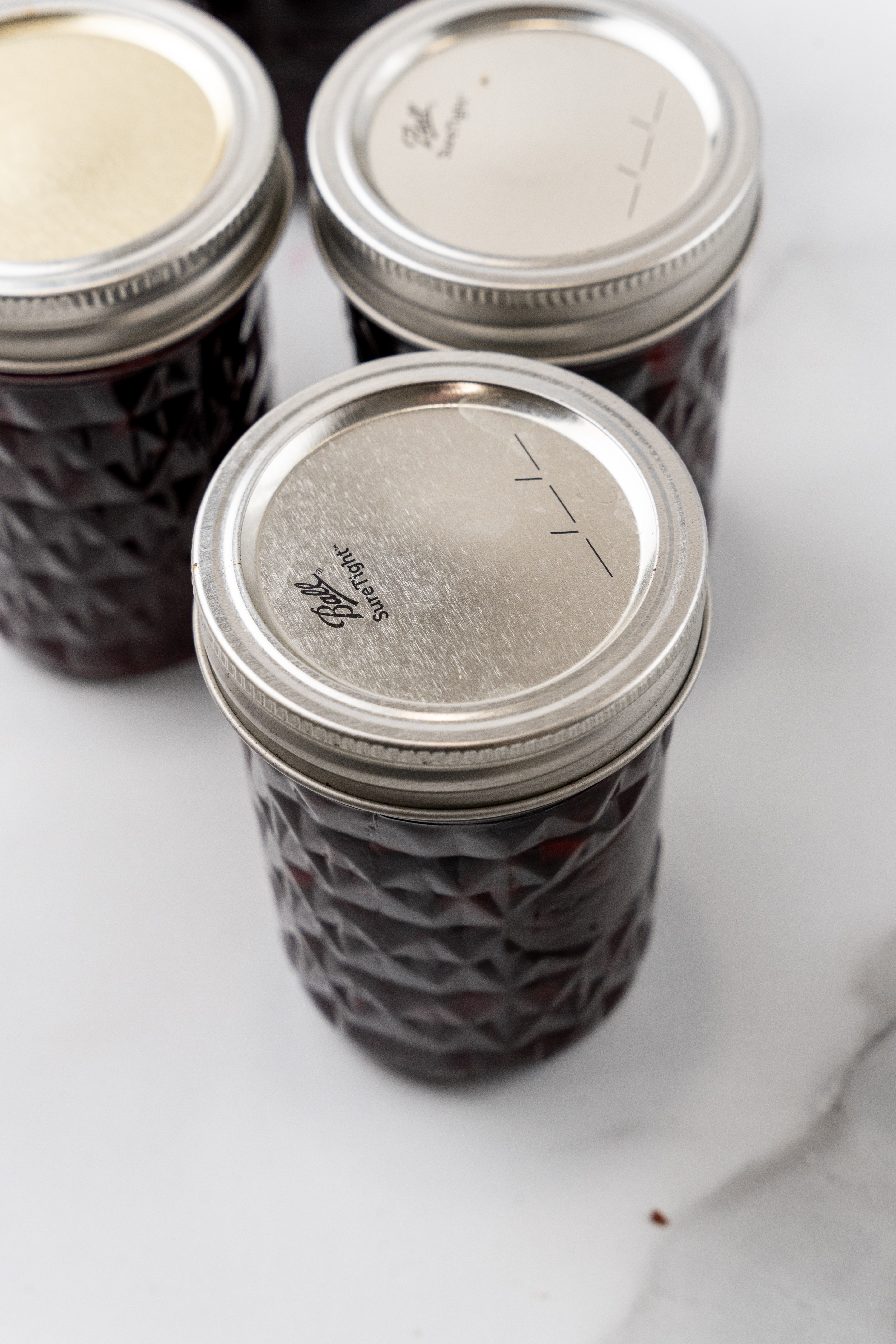 cherry habanero jam in three small glass jars with metal lids