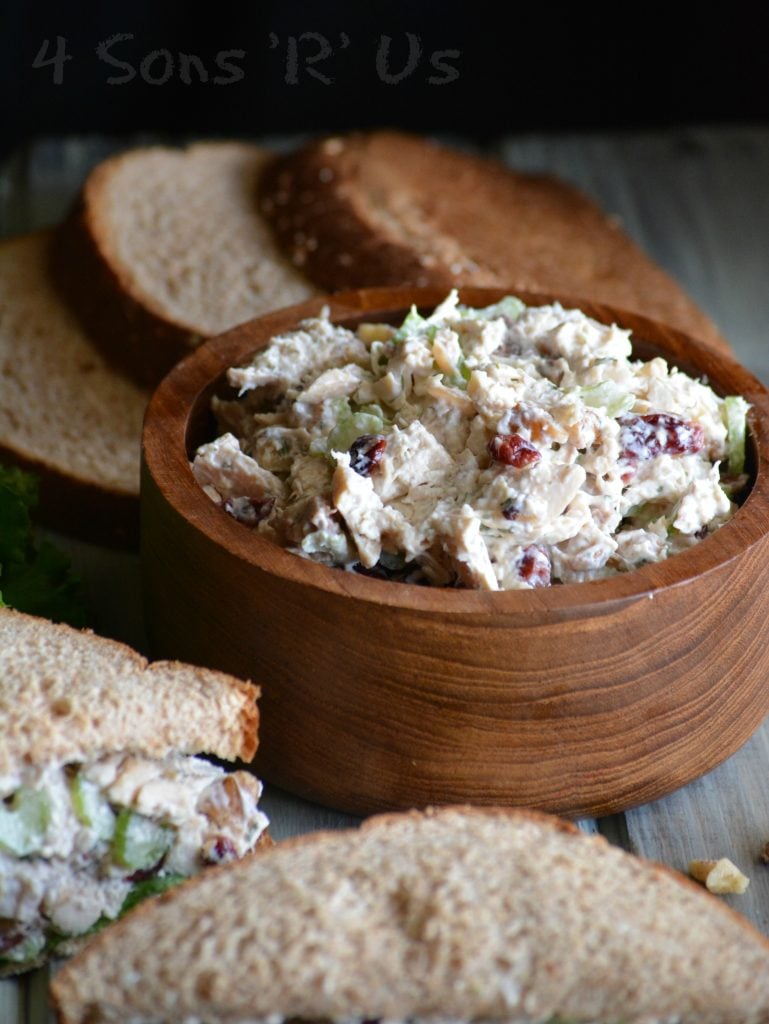 Cranberry Walnut Chicken Salad shown in a wooden bowl with sliced sandwich bread in the background