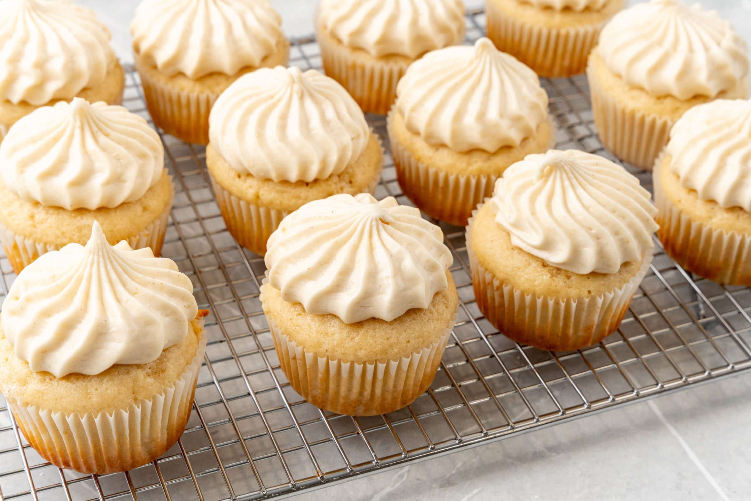 apple butter cupcakes with cinnamon cream cheese frosting on a wire cooling rack