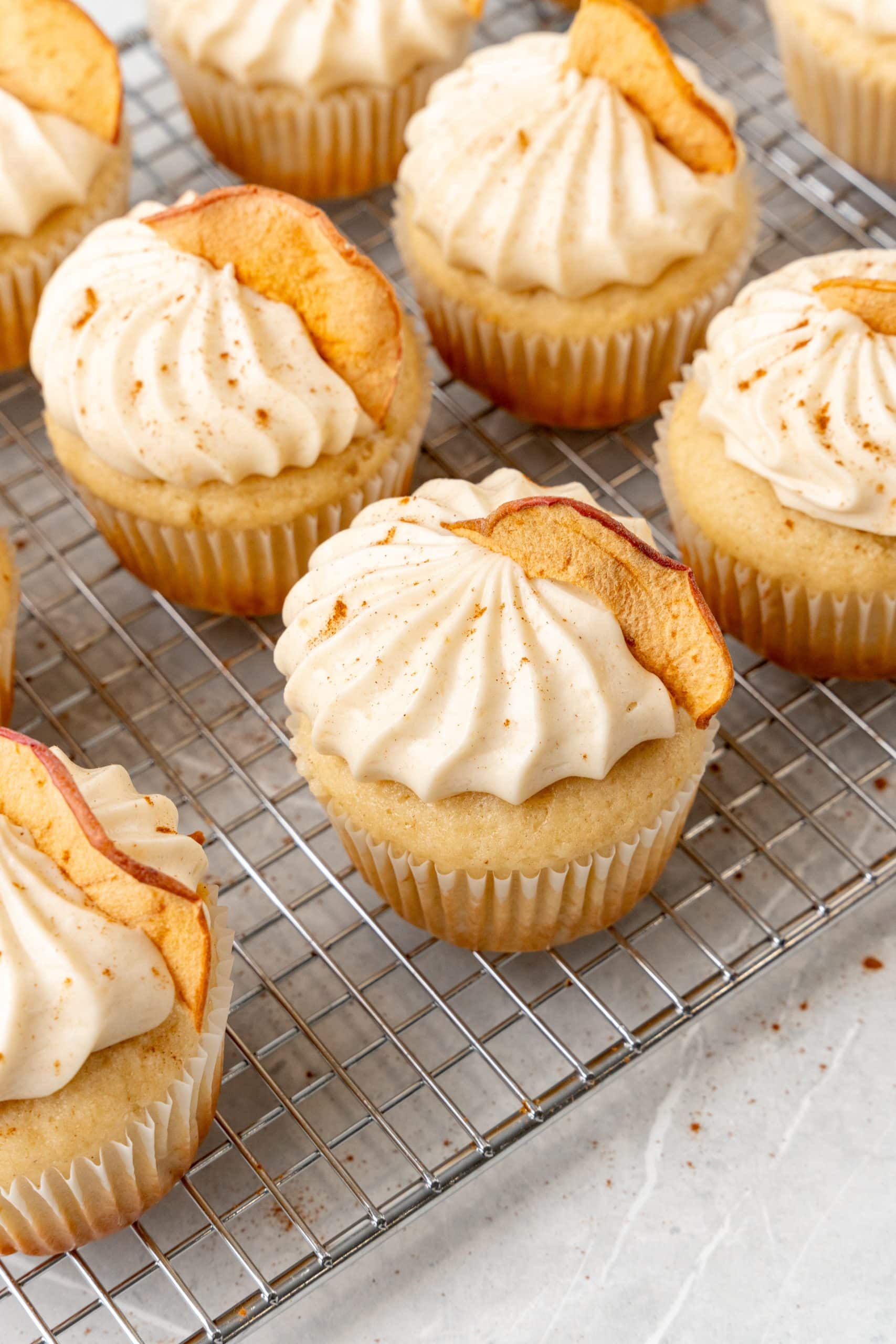 apple butter cupcakes with cinnamon cream cheese frosting on a wire cooling rack