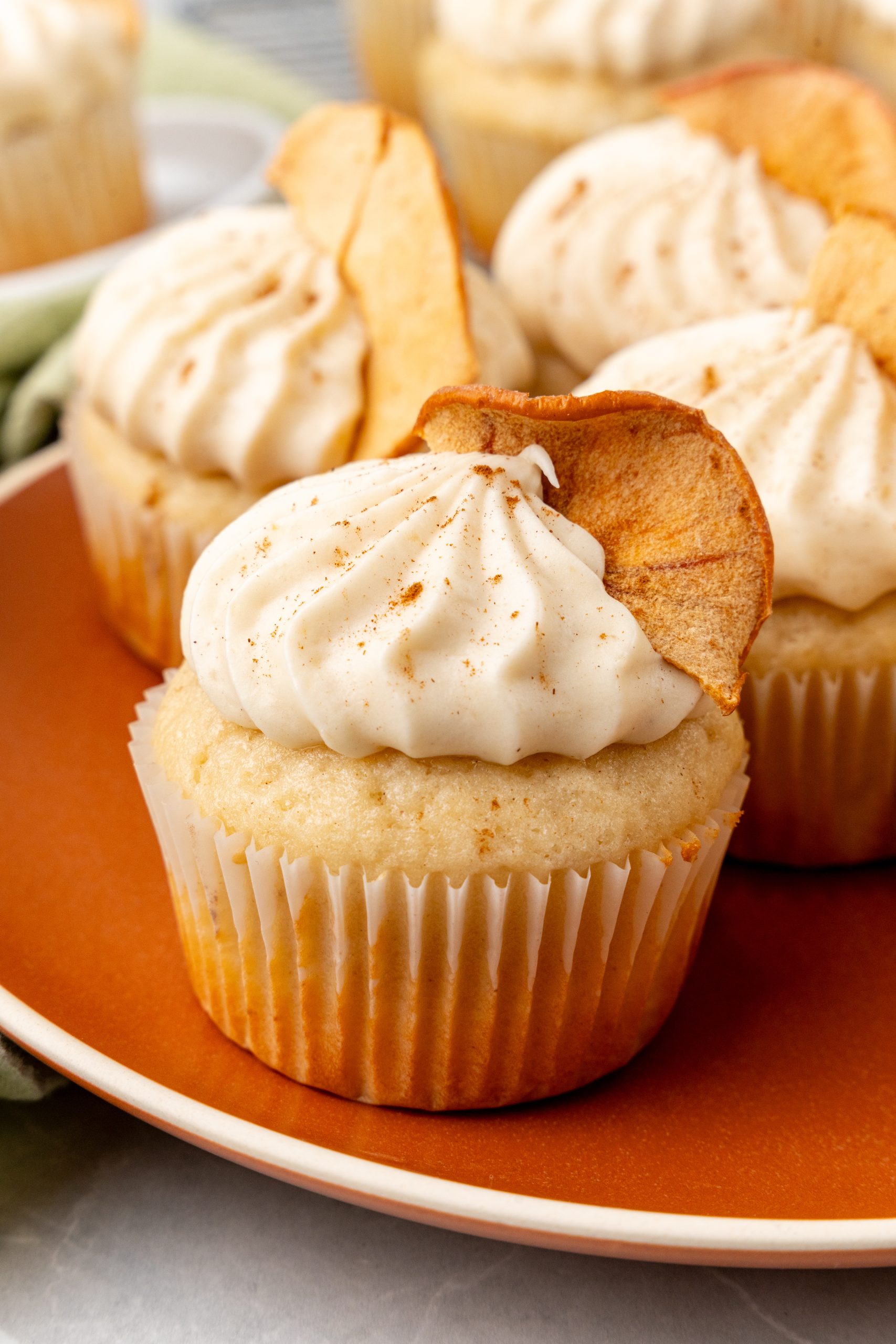 apple butter cupcakes with cinnamon cream cheese frosting on an orange plate