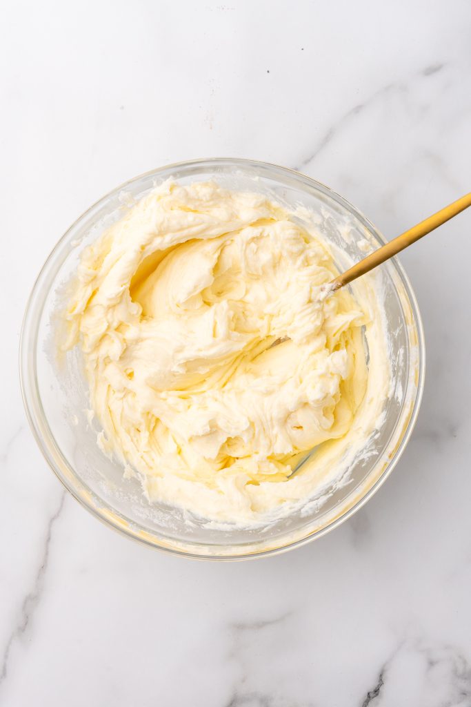 creamed cheese and sugar whipped together in a glass mixing bowl