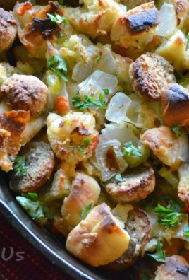 CIABATTA MEATBALL STUFFING IN A CAST IRON SKILLET WITH FRESH GREEN HERBS SPRINKLED OVER TOP