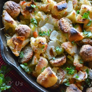 CIABATTA MEATBALL STUFFING IN A CAST IRON SKILLET WITH FRESH GREEN HERBS SPRINKLED OVER TOP