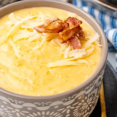asiago bisque topped with shredded cheese and bacon in a small gray bowl