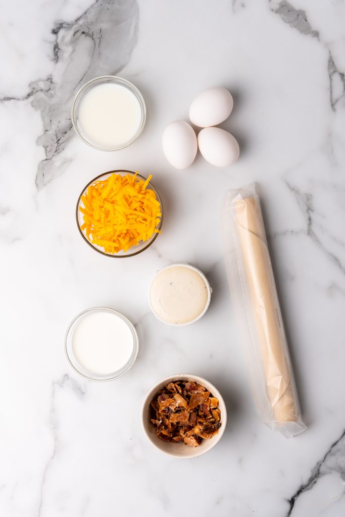 an overhead image showing the measured ingredients needed to make a cheddar bacon ranch quiche