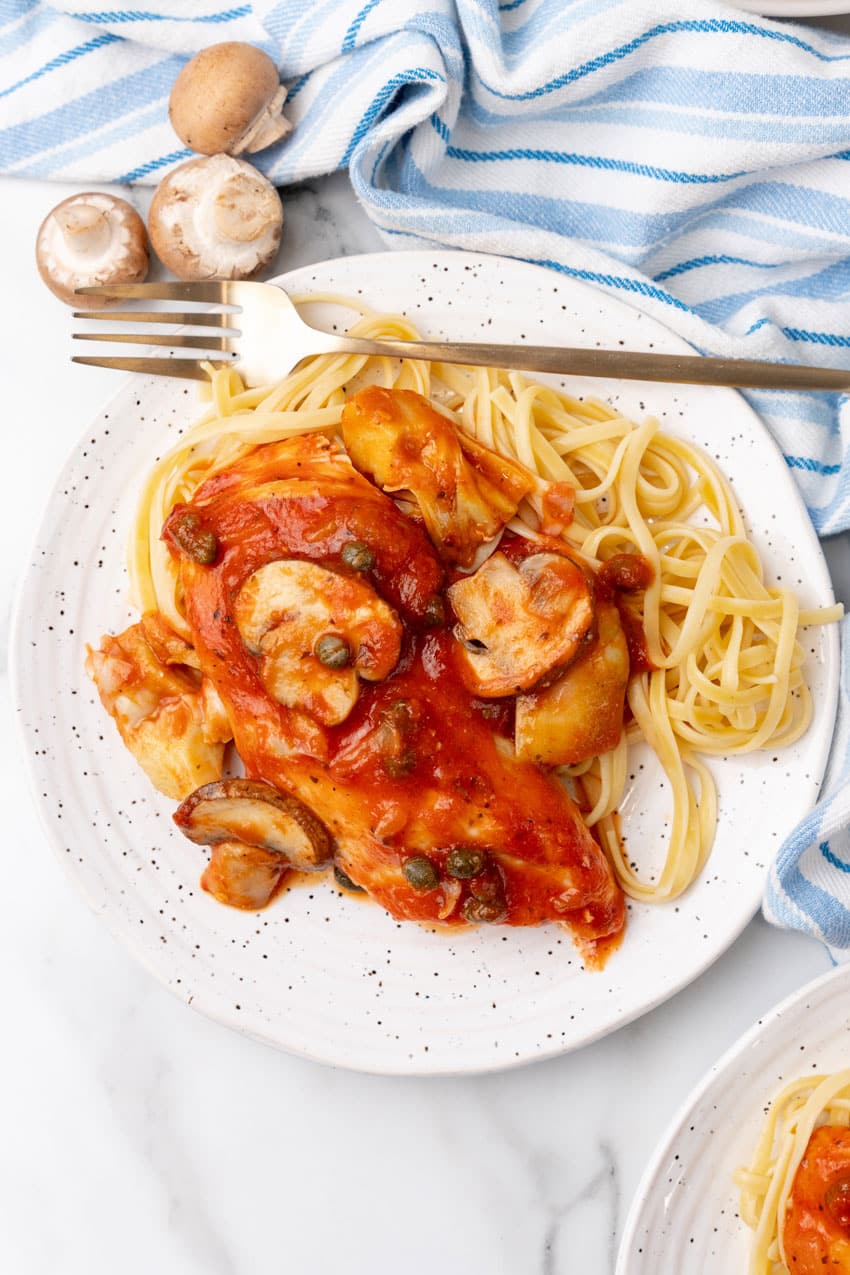 easy tuscan chicken on a white plate with a gold fork on the side