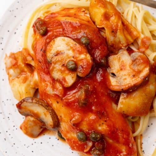 easy tuscan chicken on a white plate with a gold fork on the side