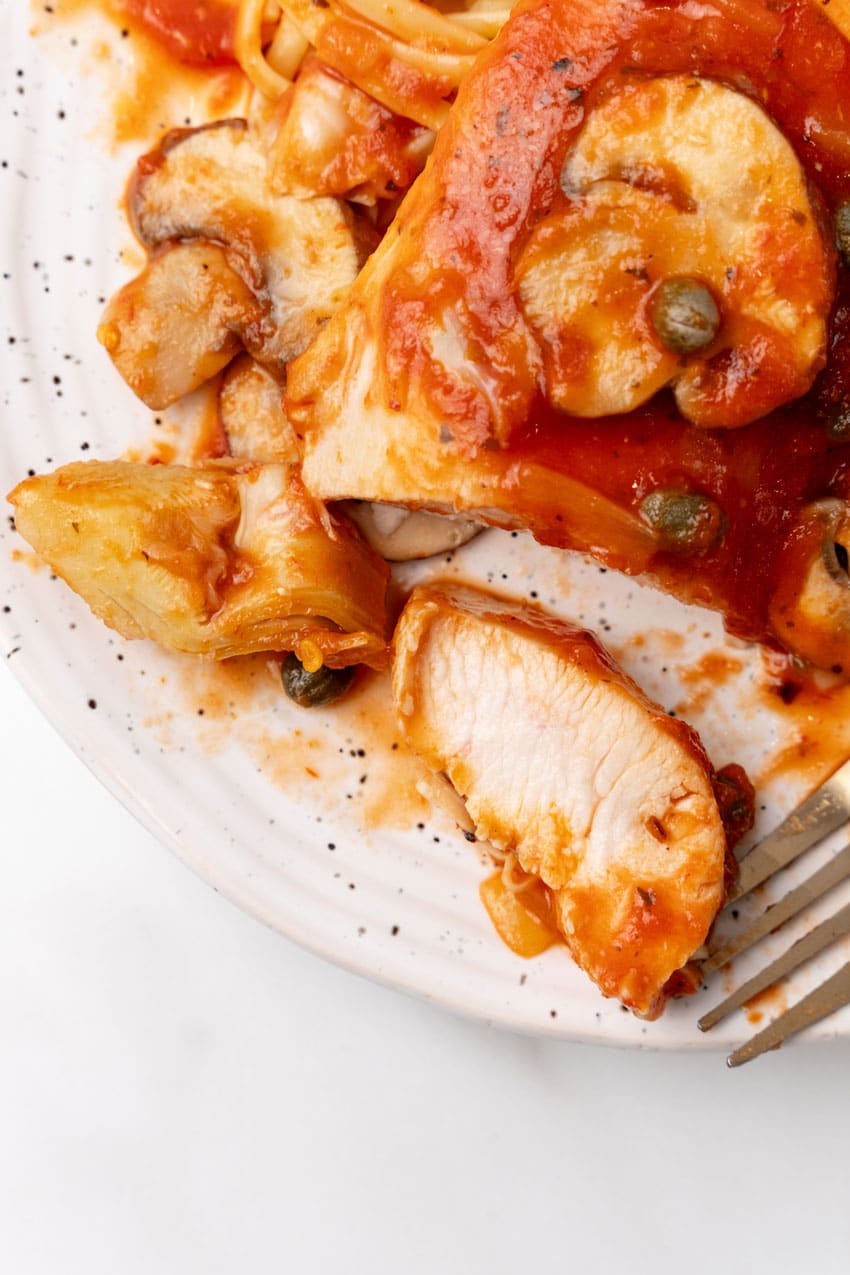 easy tuscan chicken on a white plate with a gold fork on the side