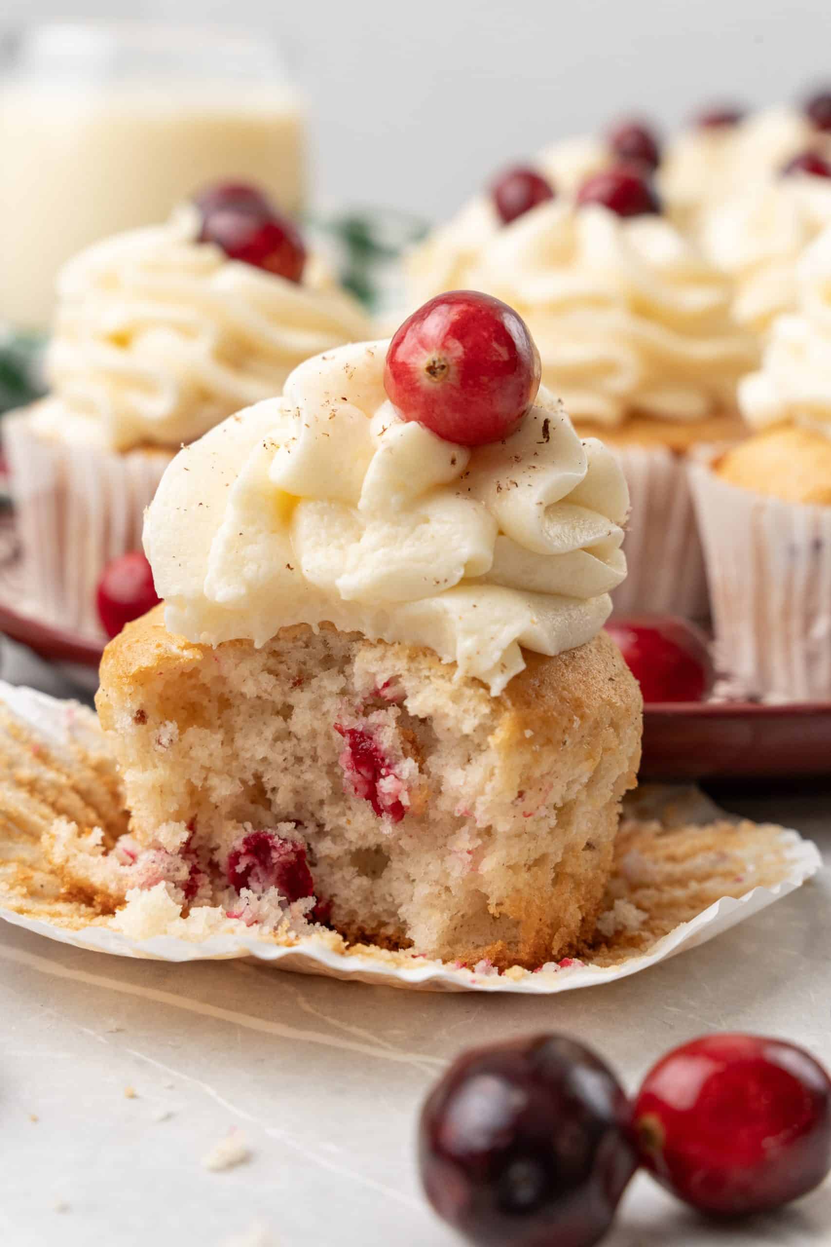 a bitten cranberry eggnog cupcake on a white table