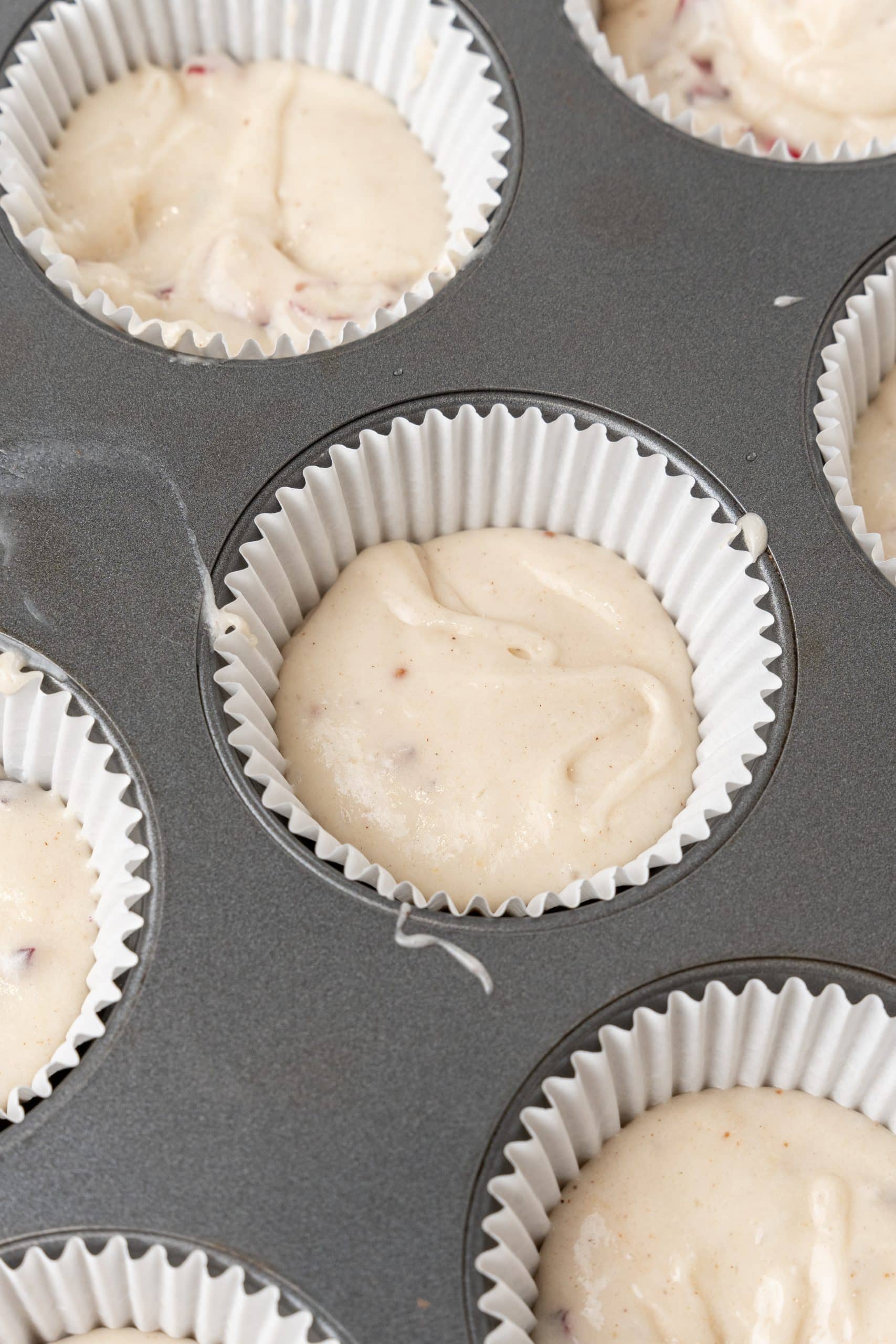 cranberry eggnog cupcake batter in cupcake liners in a muffin tin
