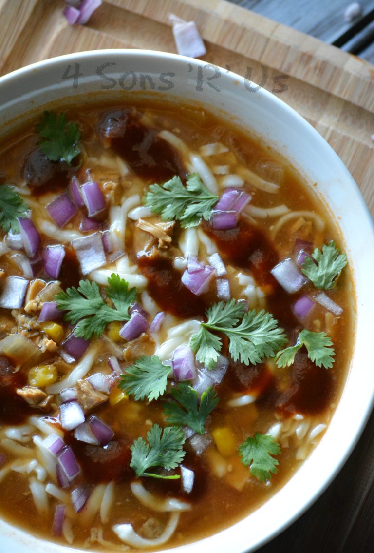 slow cooker barbecue chicken pizza soup in a white bowl on top of a wooden cutting board